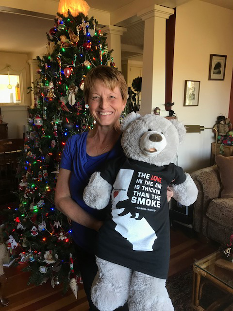 Deborah Myers holding her Sonoma Strong Bear in front of the Christmas Tree