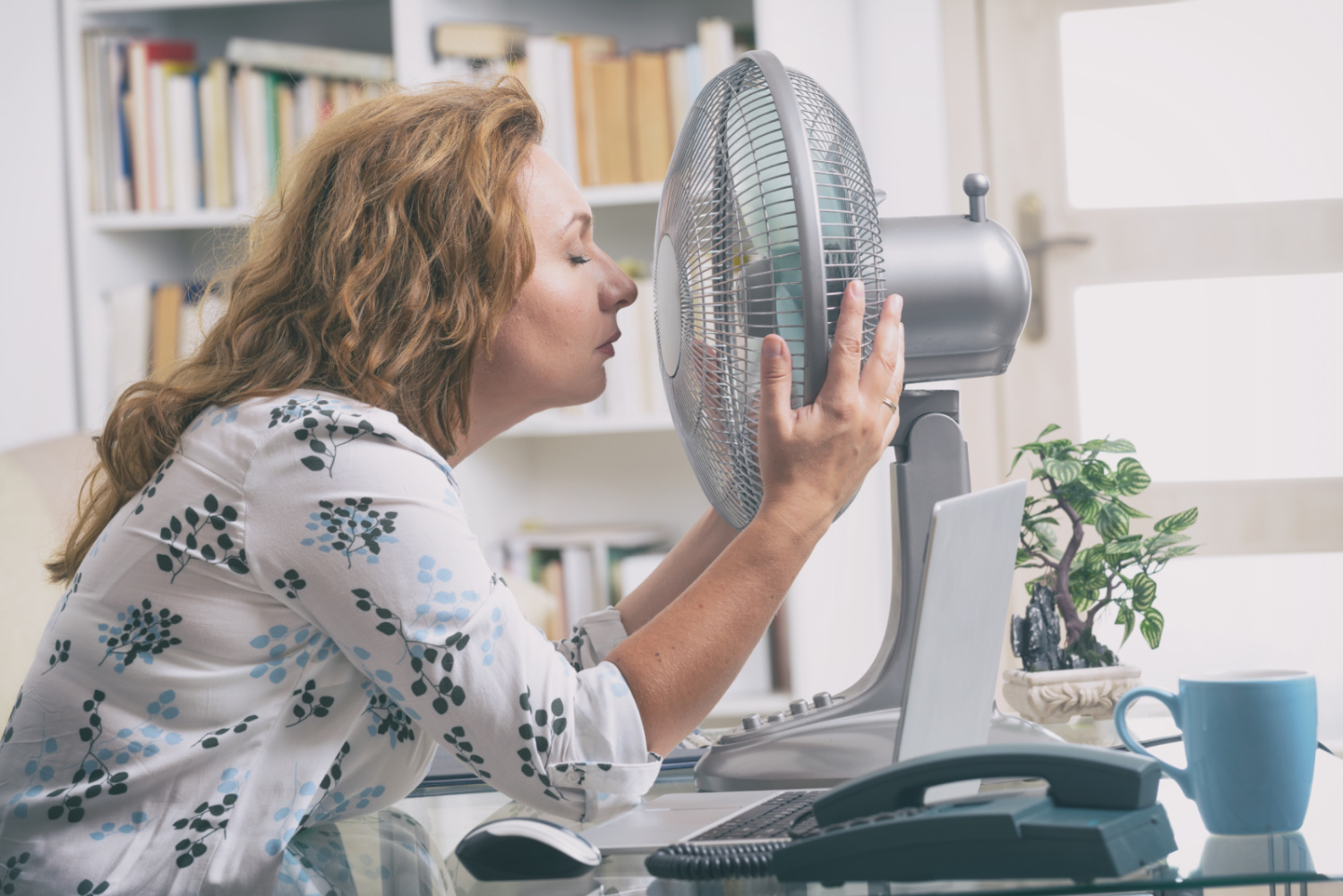 Woman cooling face with table fan