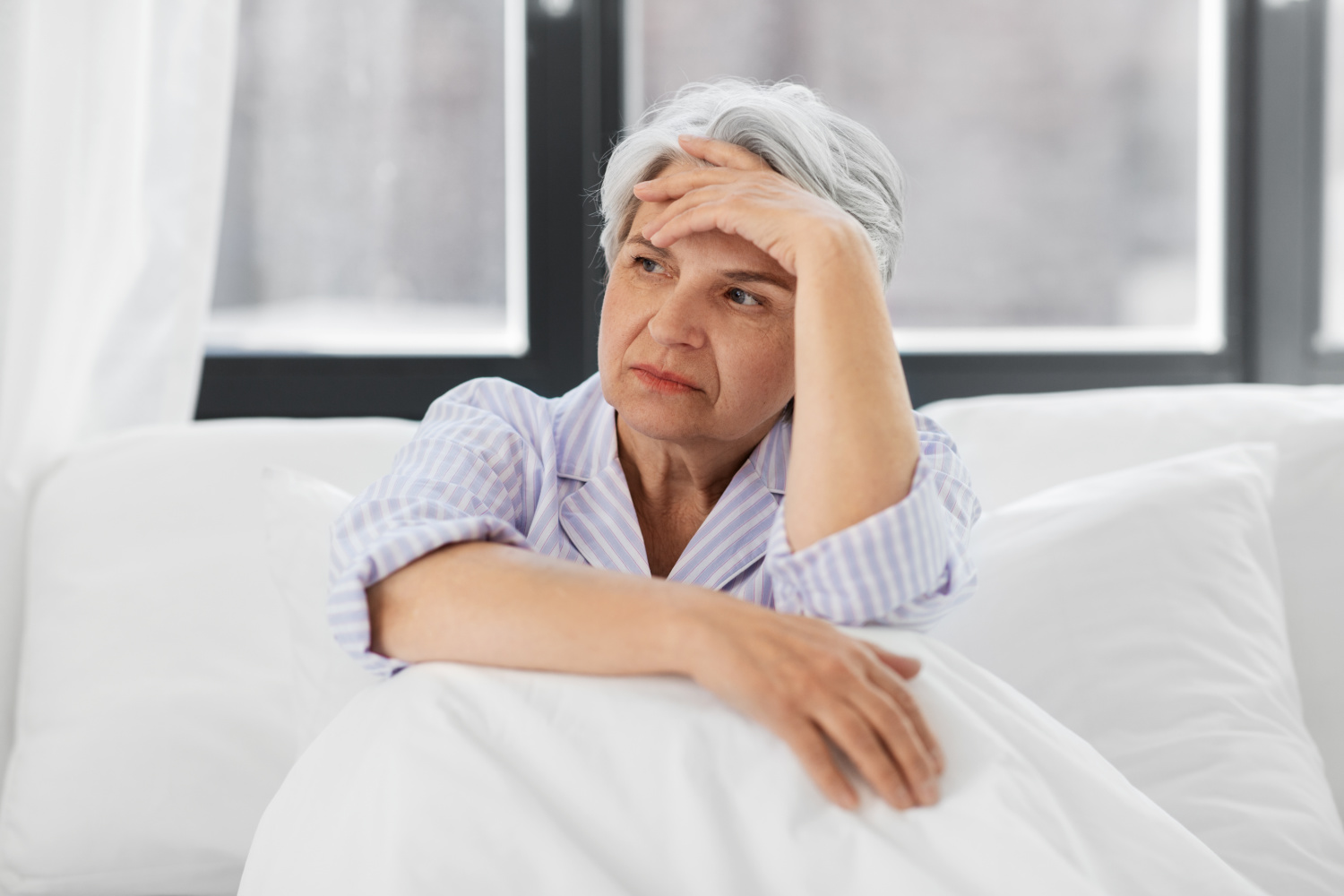 Senior women in bed looking anxious and stressed